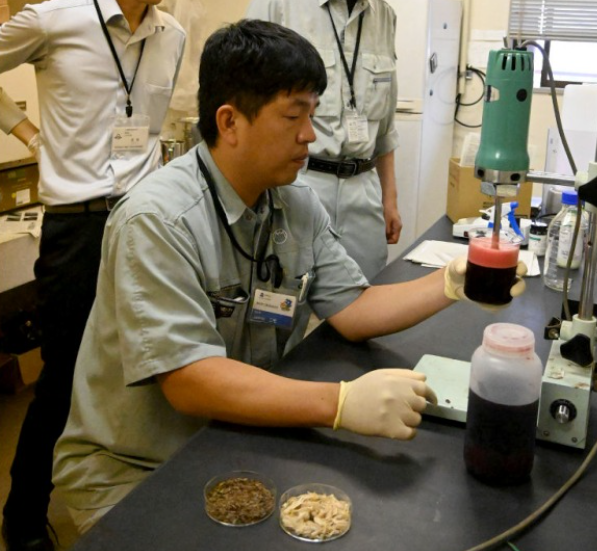 Investigadores japoneses en laboratorio analizando subproductos de salmón de acuicultura en tierra.