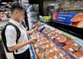 Consumidora observa salmón noruego en un supermercado de Vietnam