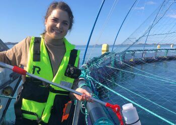 La investigadora Lisa-Victoria Bernhardt muestra el recipiente de un litro utilizado para tomar muestras de agua en jaulas noruegas.