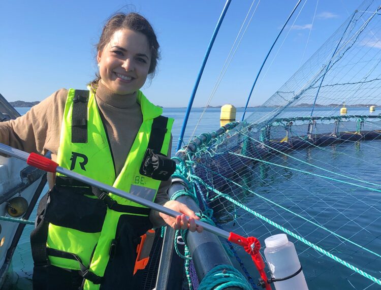 La investigadora Lisa-Victoria Bernhardt muestra el recipiente de un litro utilizado para tomar muestras de agua en jaulas noruegas.