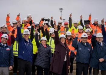 Trabajadores y autoridades con cascos levantan los brazos en una obra pública en Magallanes durante el plan Chile Despega