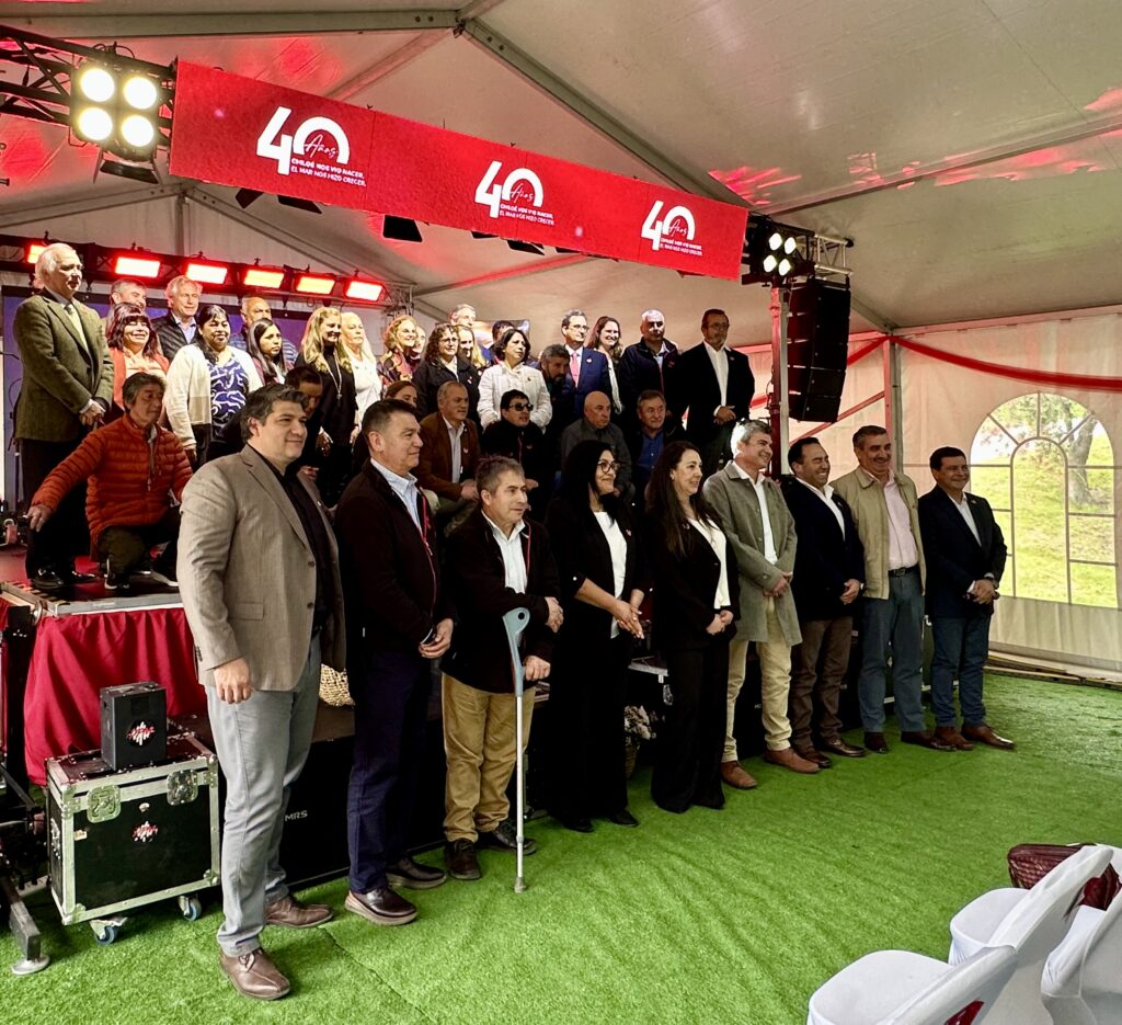 Colaboradores, ejecutivos e invitados de Salmones de Chile posan bajo el letrero de los 40 años en Chonchi, Chiloé