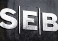 Logotipo de SEB en letras metálicas sobre una pared oscura.