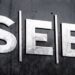Logotipo de SEB en letras metálicas sobre una pared oscura.