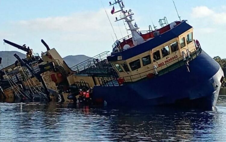 Wellboat Vali escorado y semihundido en aguas cercanas a Melinka con la popa bajo el mar.
